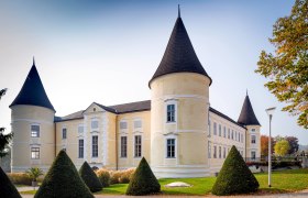 Gelbes Schloss mit Türmen und gepflegtem Garten im Herbst., © foto-hoefinger.at